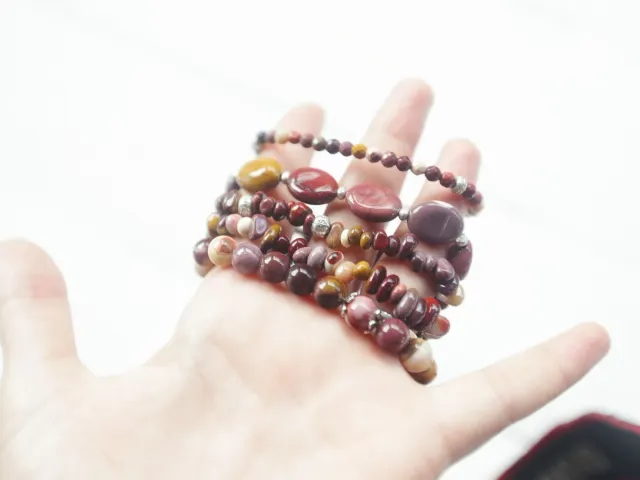 Burgundy, honey and cream beaded bracelets displayed on a hand